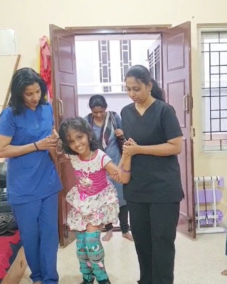 Two physiotherapists helping a child walk